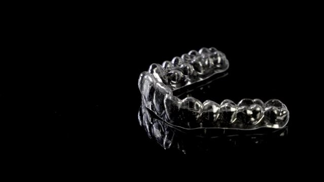 Invisible orthodontics cosmetic brackets on black background. Tooth aligners, for beautiful smile.