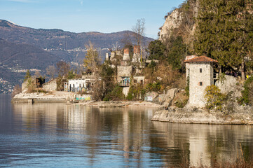 Old ruined furnaces with chimneys with red bricks reflecting on the water of Lake Maggiore in the Parco delle Fornaci in Caldè