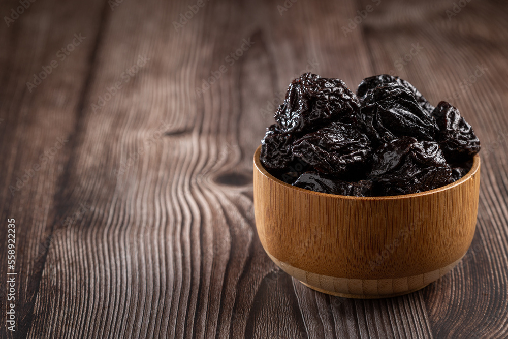 Wall mural Bowl with prunes on the table.