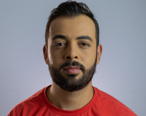 Homem moreno de cabelo curto e barba vestindo uma camiseta laranja com i