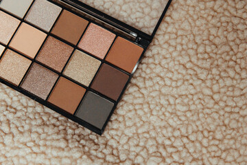 Eyeshadow palette in warm colors on a plain textural background. For stylists, make-up artists,...