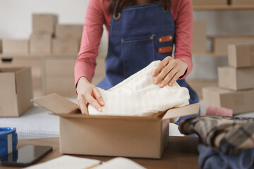 Online shopping business concept, Women entrepreneur packing clothes in box for delivery to client
