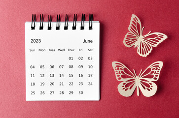 The June 2023 desk calendar for the organizer to plan and reminder with paer butterfly on red background.