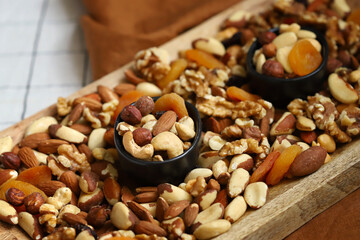 Mix of nuts and dried fruits on a wooden board and in a bowl. Healthy sweets.