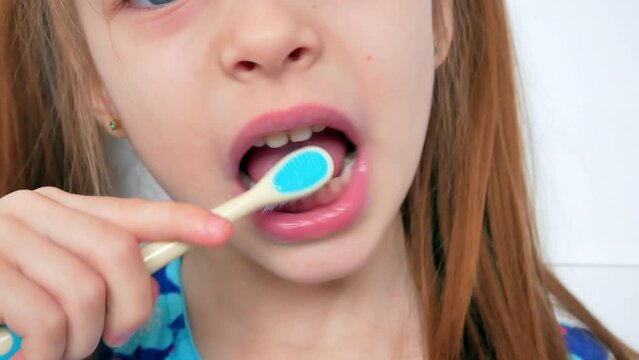 A little girl brushes her teeth with her mouth in close-up. Protection against caries of the oral cavity. Hygiene.