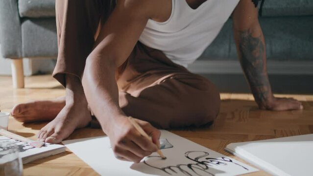 Focused creator painting picture at sofa interior. Talented guy making artwork