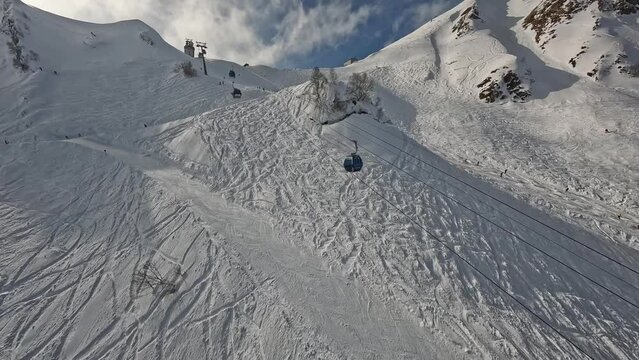 FPV drone dynamic shot ski resort people riding on slope track skiing snowboarding cableway mountain winter landscape aerial raising up view. Summit ridge gazex alpine scenery extreme sport leisure 4k