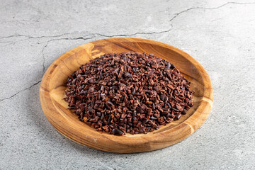 Cocoa nibs on wooden plate.