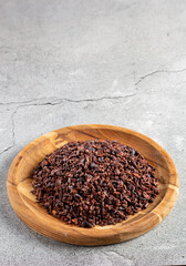 Cocoa nibs on wooden plate.
