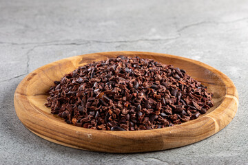 Cocoa nibs on wooden plate.