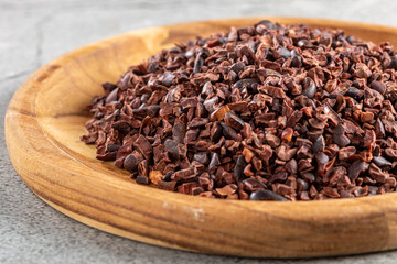Cocoa nibs on wooden plate.