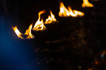 Fire flame at night with dark background during the ganga aarti rituals at river bank at Rishikesh,...