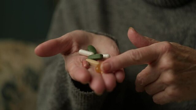 Mature Hands Holding Medicine Pills On Hand. Unrecognised Senior woman counting medicine drugs in hands.
