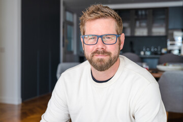 Young handsome man wearing glasses smiling at home.