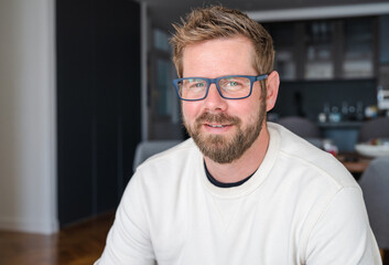 Close up portrait of smiling 30s Caucasian man look at camera posing in own flat or apartment....
