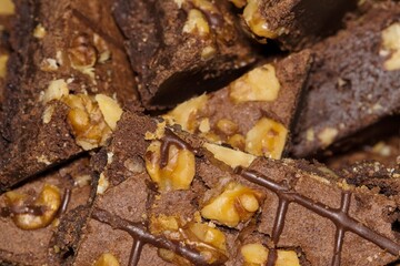 Chocolate brownies topped with walnuts piled on a serving platter. Homemade baked goods, isolated abstract closeup with selective focus.