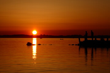 Fototapeta na wymiar Sunset at Lake Chiemsee with anglers in Ubersee Germany