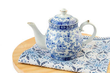 Faience teapot on a cutting board with a napkin, isolated on a white background.