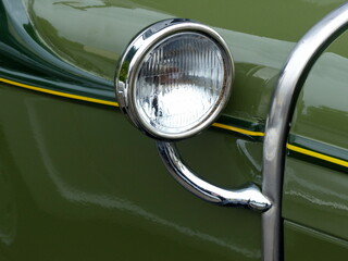Suchscheinwerfer mit Chromring einer grünen amerikanischen Limousine der Dreißigerjahre im Sommer...