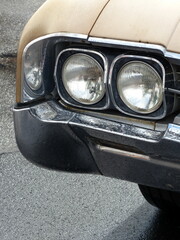 Kühlergrill mit Doppelscheinwerfer eines Oldsmobile Delta 88 der Sechziger Jahre in vergilbtem...