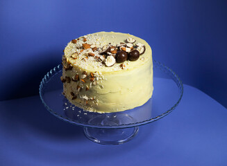 Festive banana cake in white chocolate, decorated with nuts, cookies and chocolate on a blue...
