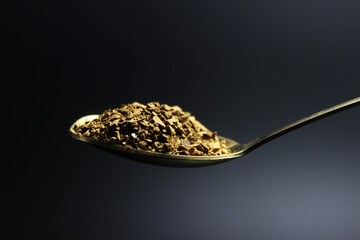 granular instant coffee in a teaspoon, isolated on black background