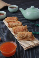Dimsum, as the name Keicak, is filled with carrots, chicken, mushrooms and wrapped in tofu skin, side angle with black background