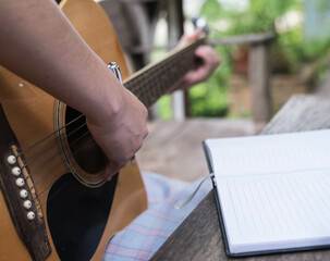 songwriter thinking and writing notes,lyrics in book at studio.man playing live acoustic...