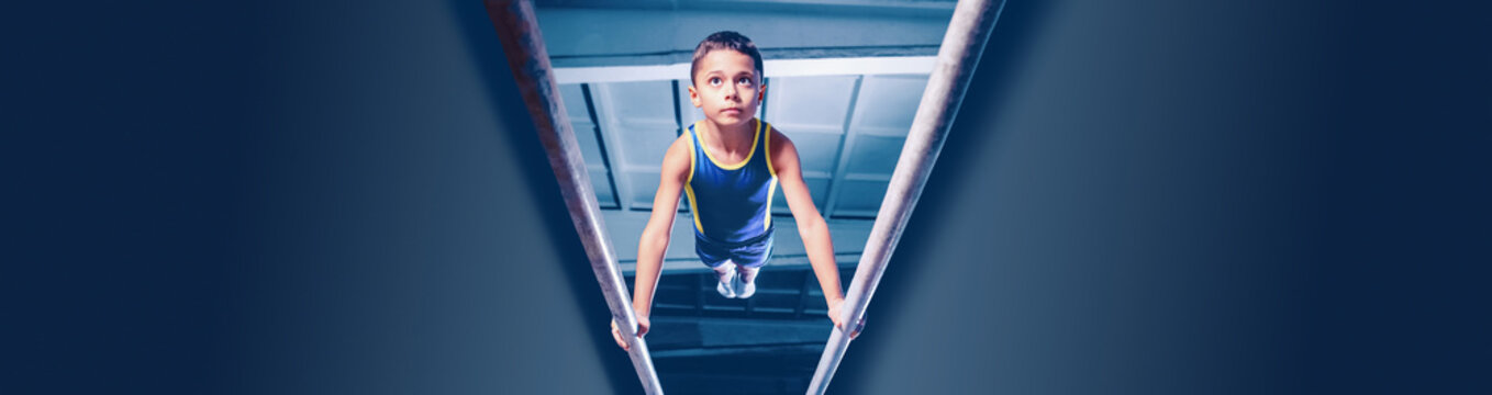 Image of little boy, child training, doing gymnastics exercises on parallel bars at gym. Developing strength and endurance