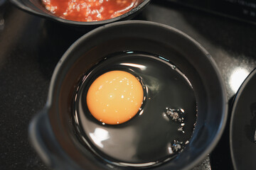 Egg and yolks in a black bowl. Ingredients for omelette