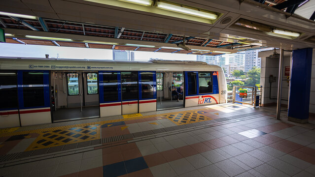 Kuala Lumpur, Malaysia - August 21, 2022: Train of the Rapid KL public transport system at the platform of the Asian Jaya Train station. Railroad tracks meander through the city above the streets