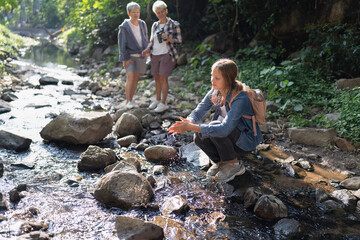 Backpack tourist travel hiking outdoor adventure walking in row on rock side of water stream flow