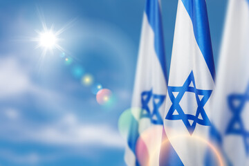 Israel flags with a star of David over cloudy sky background. Patriotic concept about Israel with...
