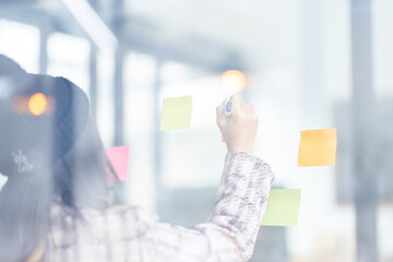 Business female employee with many conflicting priorities arranging sticky notes commenting and...