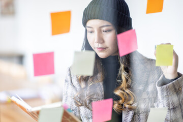 Business female employee with many conflicting priorities arranging sticky notes commenting and...