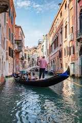 Obraz na płótnie Canvas Gondolier rowing gondola on canal in Venice, Italy.