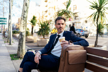 Mature businessman with takeaway coffee in street - 558946892