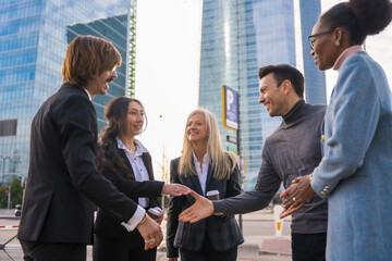 Group of multi-ethnic business people in a business park introducing themselves and shaking hands...