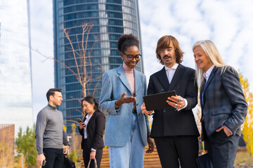 Multi-ethnic business colleagues or executives, looking at technologies, business park exterior