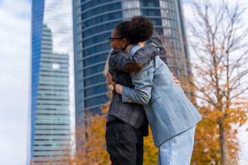 Middle-aged multi-ethnic businesswomen and executives, hugging outside the office