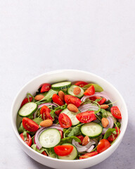Healthy salad with spelt, oranges, pomegranate seeds. greens and nuts on light background, minimal style