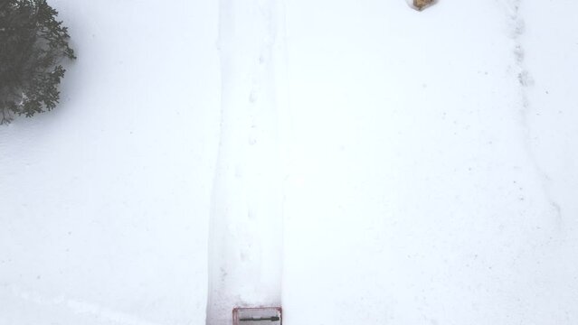 Aerial overhead view of snow blowing a residential sidewalk. 
