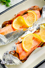 Baked Salmon in Foil, Cooked Fish with Vegetables in a baking dish on Bright Backround, Healthy Eating