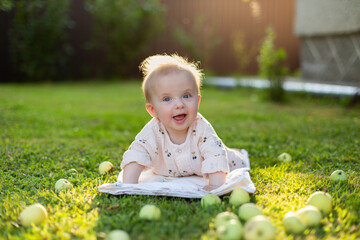 Happy smiling caucasian baby laying on the grass with the apples