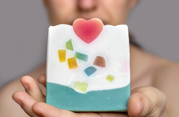 woman using handmade soap with red heart shape on top and colorful pieces.smiling girl holding soap on shoulder or chest isolated valentine's day do it yourself beauty skin face body care copy paste