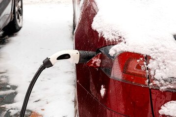 Charging an electric vehicle in winter. Charging station. Eco-friendly transport