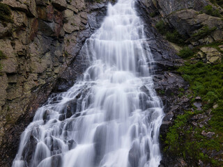 natural waterfall from the rocks in the mountain forest. transparent water