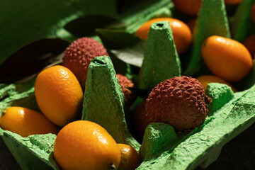 Lychees and cumquats in a green box. Close up.