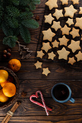 Ginger cookies in the shape of stars on the grill, next to fir twigs and a mug of tea