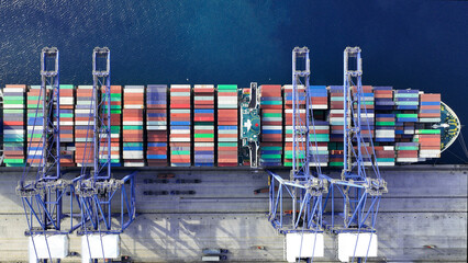 Aerial top down photo of industrial cargo container ship being loaded by large cranes in logistics...